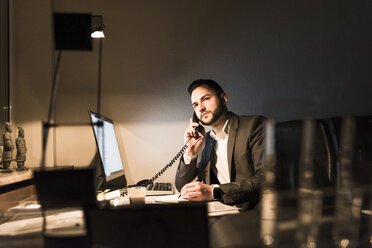 Geschäftsmann am Telefon im Büro bei Nacht - UUF13210