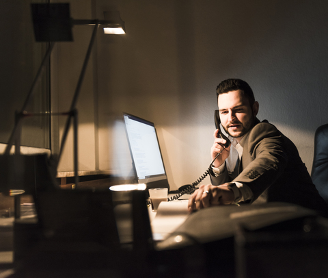 Businessman on the phone in office at night stock photo