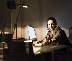 Geschäftsmann am Telefon im Büro bei Nacht - UUF13211