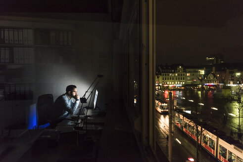 Businessman working on computer in office at night - UUF13213