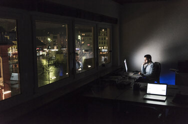 Geschäftsmann bei der Arbeit am Computer im Büro bei Nacht - UUF13214