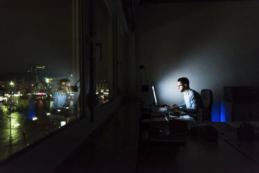 Geschäftsmann arbeitet am Computer in einem dunklen Büro - UUF13215