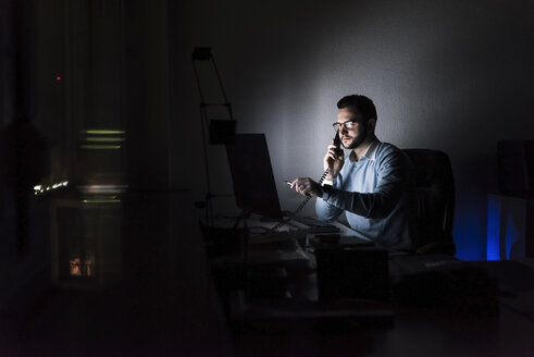 Geschäftsmann am Telefon im Büro bei Nacht - UUF13217