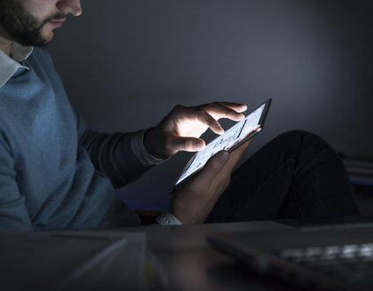 Geschäftsmann arbeitet nachts im Büro an einem Tablet, Nahaufnahme - UUF13224