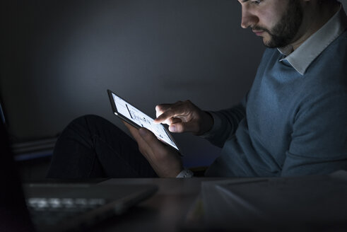 Geschäftsmann arbeitet nachts im Büro am Tablet - UUF13225