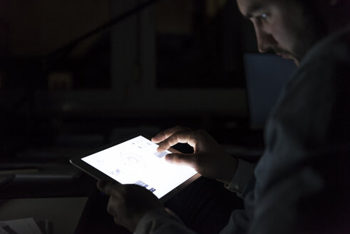 Geschäftsmann arbeitet im Dunkeln an einem Tablet, Nahaufnahme - UUF13226