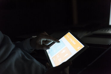 Geschäftsmann arbeitet im Dunkeln an einem Tablet, Nahaufnahme - UUF13228