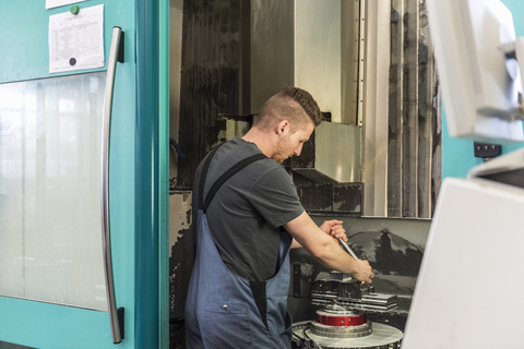 Mann arbeitet an einer Maschine in einer Fabrik, lizenzfreies Stockfoto