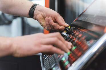 Close-up of man operating machine in factory - DIGF03662