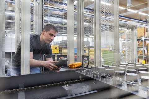 Mann bedient Maschine in Fabrik, lizenzfreies Stockfoto