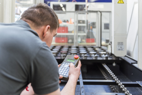 Mann bedient Maschine in Fabrik, lizenzfreies Stockfoto