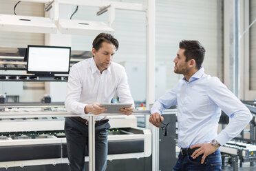 Zwei Geschäftsleute mit Tablet im Gespräch in einer modernen Fabrik - DIGF03701