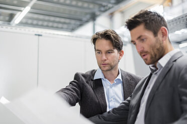 Two businessmen looking at plan in modern factory - DIGF03727