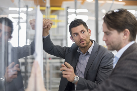 Two businessmen discussing plan in modern factory stock photo