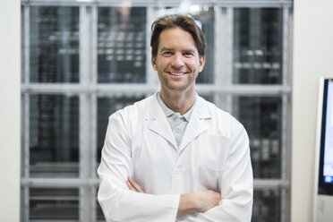 Portrait of smiling man wearing work coat in factory - DIGF03746