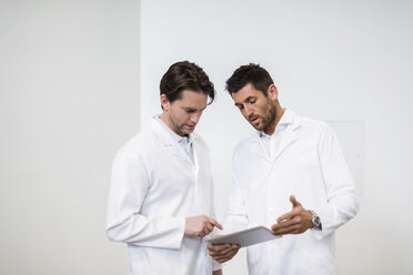 Zwei Männer in Arbeitskitteln teilen sich ein Tablet - DIGF03747