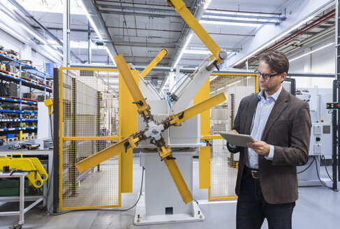 Geschäftsmann benutzt Tablet in einer Fabrikhalle - DIGF03752