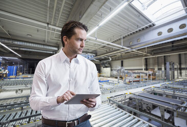 Businessman using tablet on factory shop floor - DIGF03753