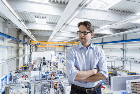 Selbstbewusster Geschäftsmann in einer Fabrikhalle, der sich umschaut, lizenzfreies Stockfoto