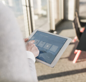 Frau verwendet Tablet mit Smart-Home-Steuerungsfunktionen im Büro - UUF13265