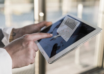 Woman using tablet in office with data emerging from screen - UUF13267