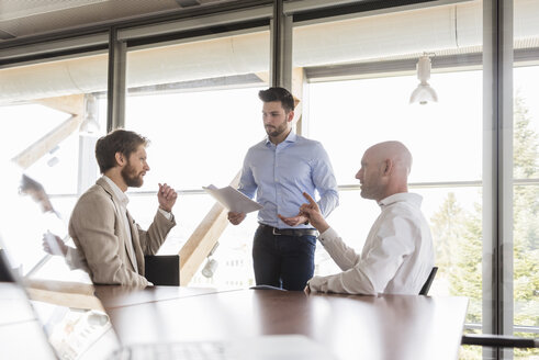 Drei Geschäftsleute besprechen sich in einem Konferenzraum - DIGF03764
