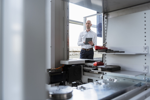 Geschäftsmann mit Tablet im Unternehmen, der ein Produkt betrachtet, lizenzfreies Stockfoto