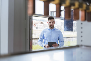 Geschäftsmann mit Tablet im Unternehmen, der ein Produkt betrachtet - DIGF03778