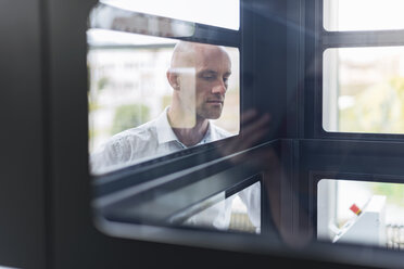 Businessman looking into glass box - DIGF03794