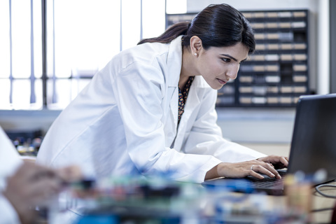 Frau in Werkstatt mit Laptop, lizenzfreies Stockfoto