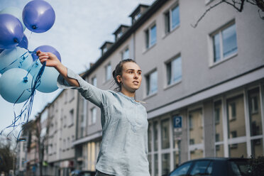 Porträt einer jungen Frau mit blauen Luftballons im Freien - GUSF00611