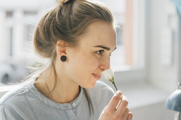 Smiling young woman smelling blossom - GUSF00615