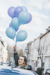 Porträt einer lächelnden Frau mit blauen Luftballons auf der Straße - GUSF00617