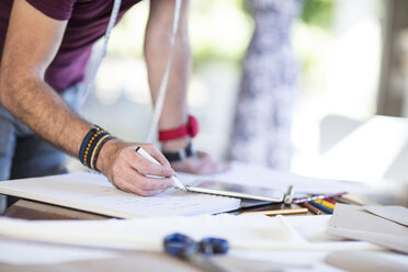 Close-up of fashion designer taking notes on table - ZEF15306