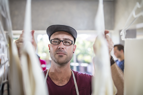 Modedesigner schaut sich im Atelier den Bestand an, lizenzfreies Stockfoto