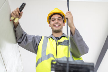 Porträt eines lächelnden Elektrikers auf einer Baustelle - ZEF15339