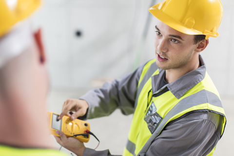 Electricians working with voltmeter on construction site stock photo