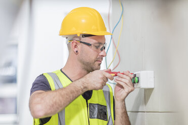 Elektriker schraubt Kabel auf einer Baustelle ein - ZEF15348