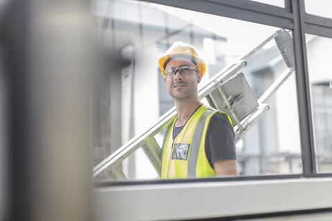 Construction worker carrying ladder stock photo