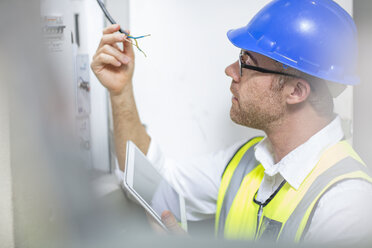 Elektriker prüft Kabel am Sicherungskasten - ZEF15359