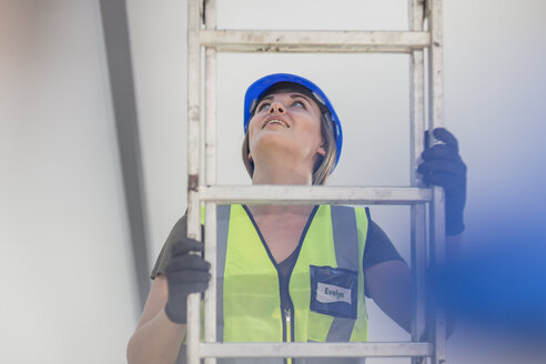 Junge Frau auf einer Baustelle klettert auf eine Leiter - ZEF15371