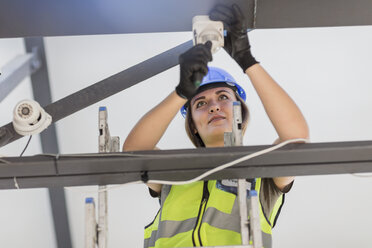 Young female electrician installing lamp - ZEF15372