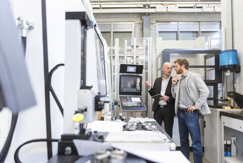 Zwei Geschäftsleute mit Tablet im Gespräch in einer modernen Fabrik - DIGF03812