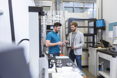 Two men with tablet talking in modern factory - DIGF03817