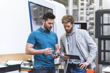 Zwei Männer mit Tablet im Gespräch in einer modernen Fabrik - DIGF03818