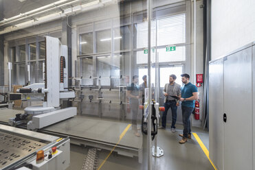 Two men looking at machine in modern factory - DIGF03828