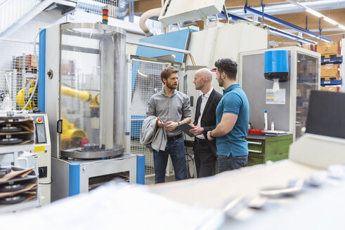 Geschäftsmann und Mitarbeiter diskutieren in einer modernen Fabrik - DIGF03836