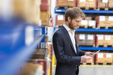 Businessman using tablet in factory storeroom - DIGF03852