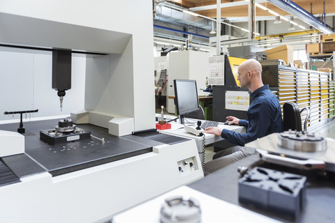 Man using computer at machine in modern factory stock photo