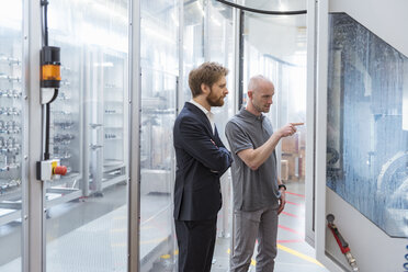 Businessman and employee talking at machine in modern factory - DIGF03868